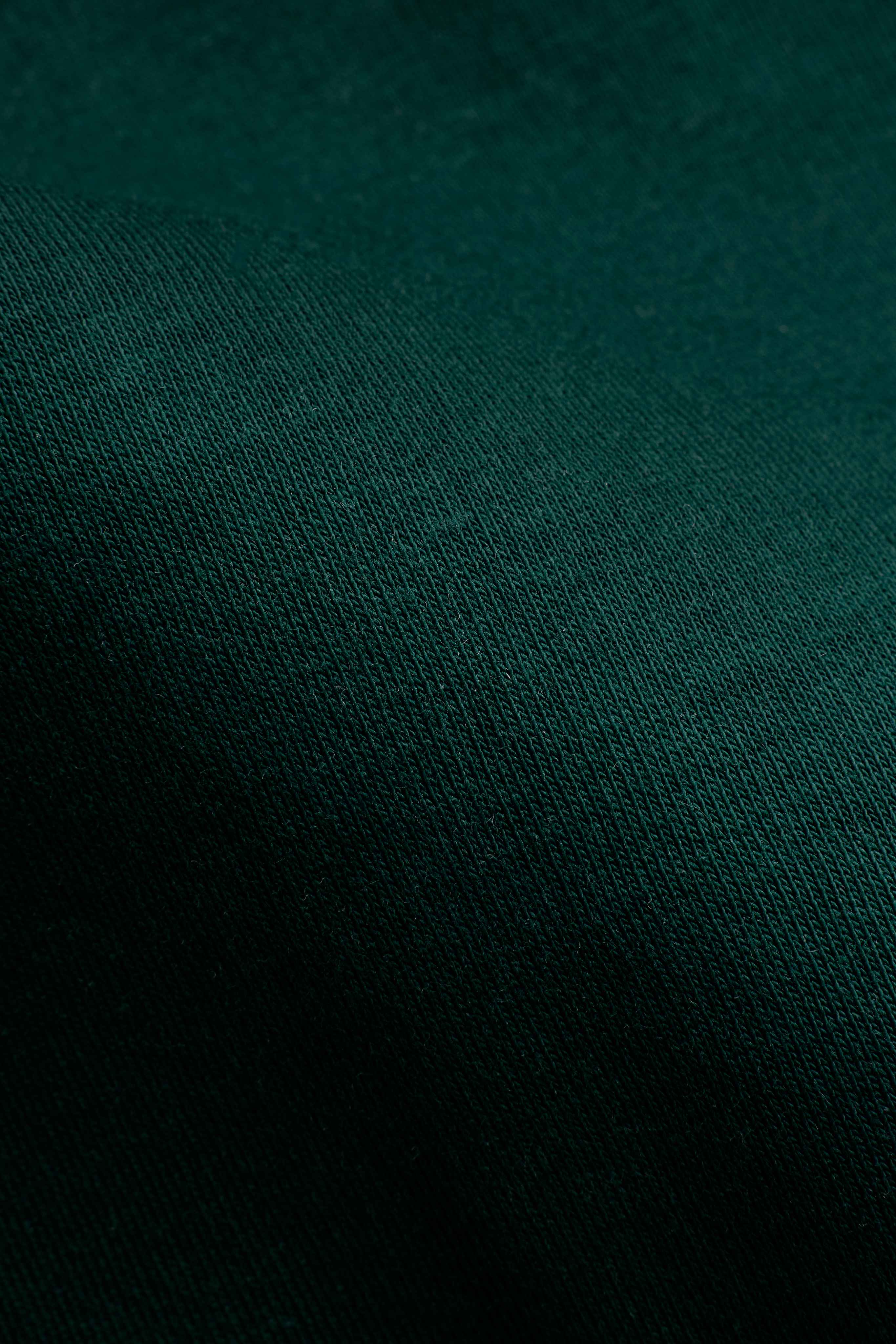 Close-up of the racing green Pima cotton knit texture on a CASPARA hoodie.